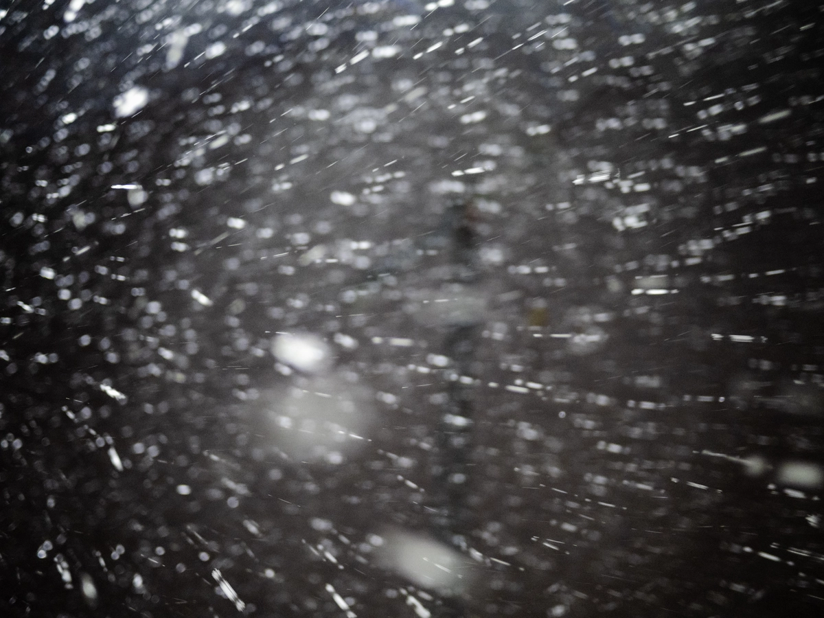 Snowflakes caught in a flash against the dark night sky