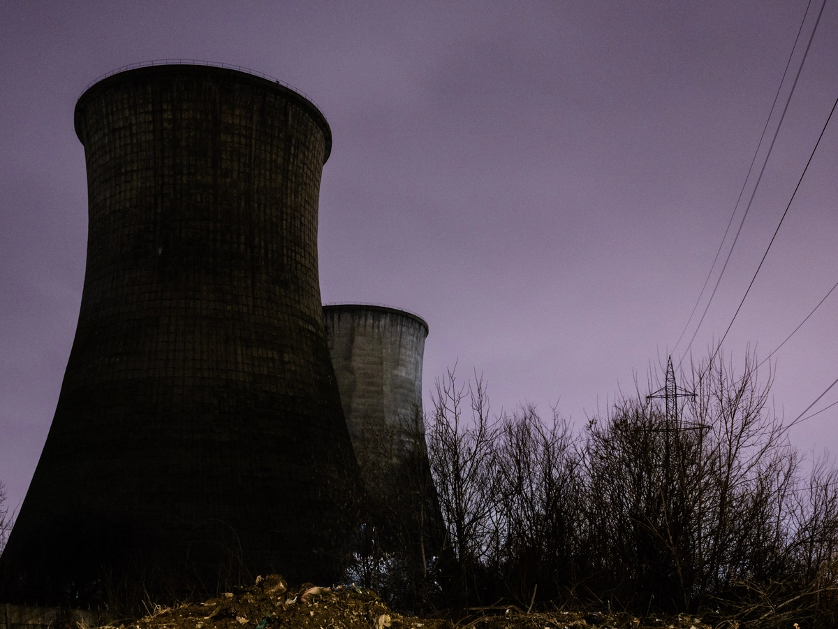 Two concrete cooling towers silhouetted against a purple dusk sky