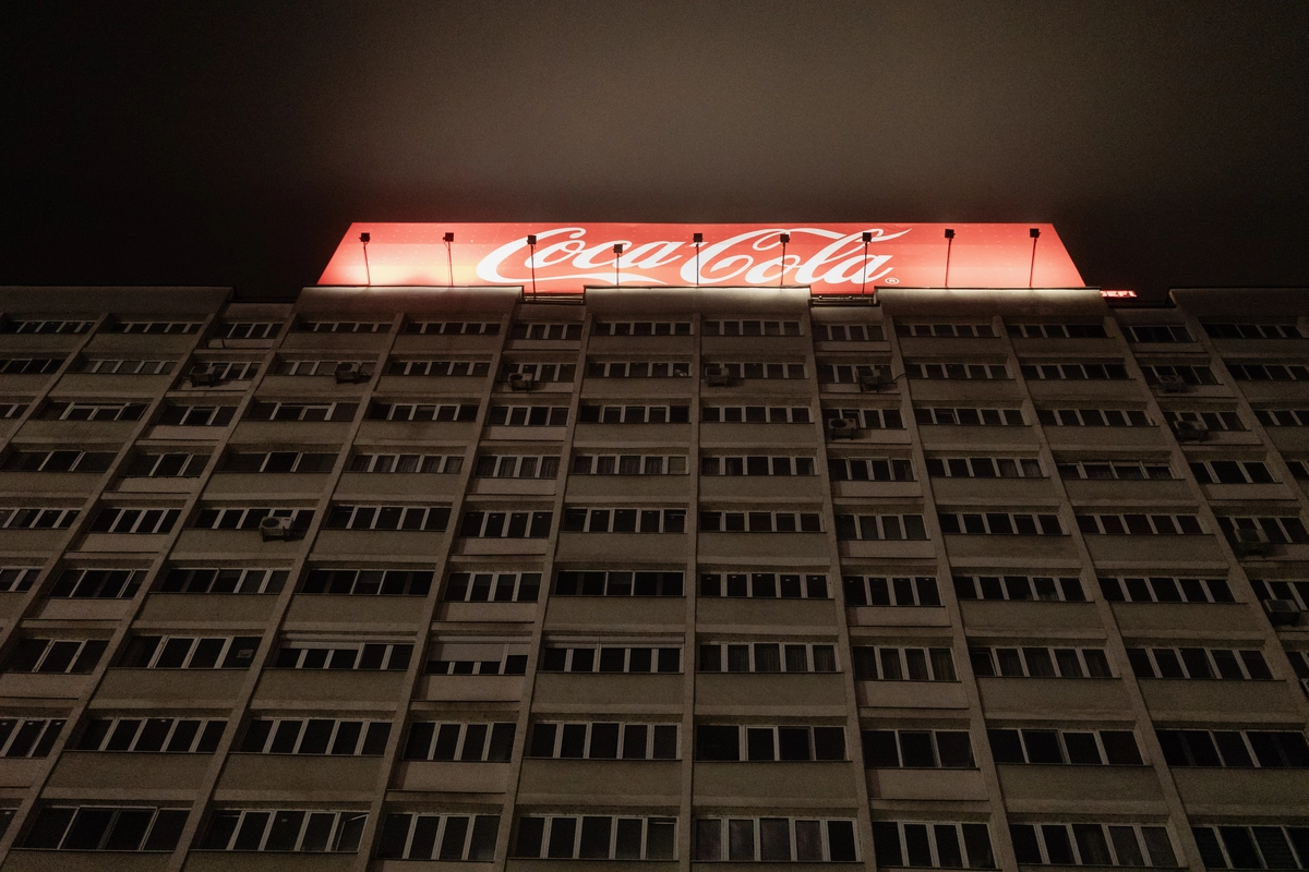 Neon Coca-Cola sign glowing atop a dark building facade at night