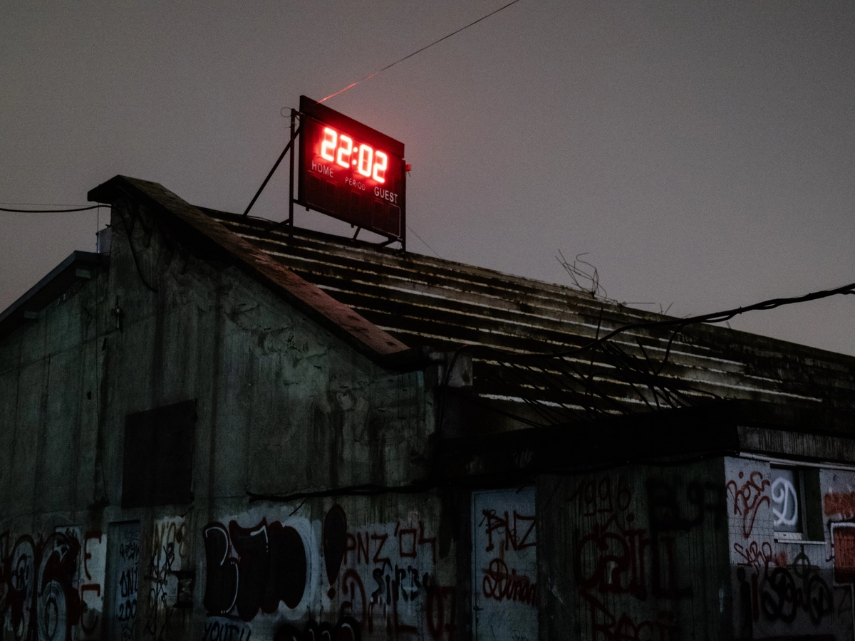 Digital clock reading 22:02 on a graffitied rooftop at dusk